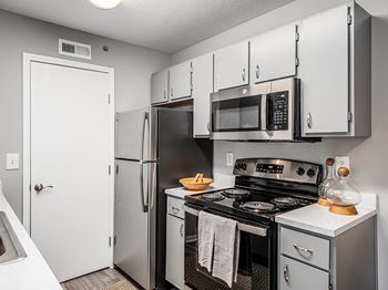 A kitchen with a stove, refrigerator, and microwave.